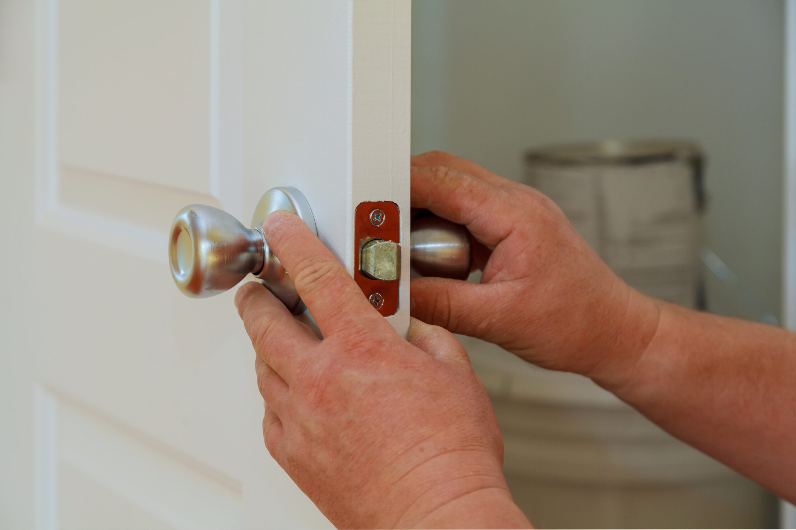 Closeup of a professional locksmith installing or repairing a new deadbolt lock on a house door with the inside internal parts of the lock visible.